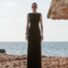 Lara olive green crepe maxi dress by Nana Gotti, featuring a sleeveless fitted silhouette and round neckline, photographed by the sea.