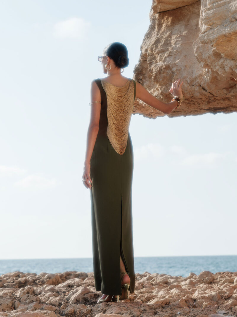 Back view of Nana Gotti Lara olive green maxi dress featuring dramatic cascading gold chain draping and a center back slit.