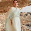 Model wearing the Nana Gotti Nerina Mint Green Fringe Cape Maxi Dress with cascading chiffon cape and fringe detailing, styled for luxury occasionwear against a natural rocky backdrop.
