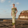 Nana Gotti Aelia olive-green botanical print maxi dress with strapless ruffles, fitted silhouette, and fringe hem by the sea.