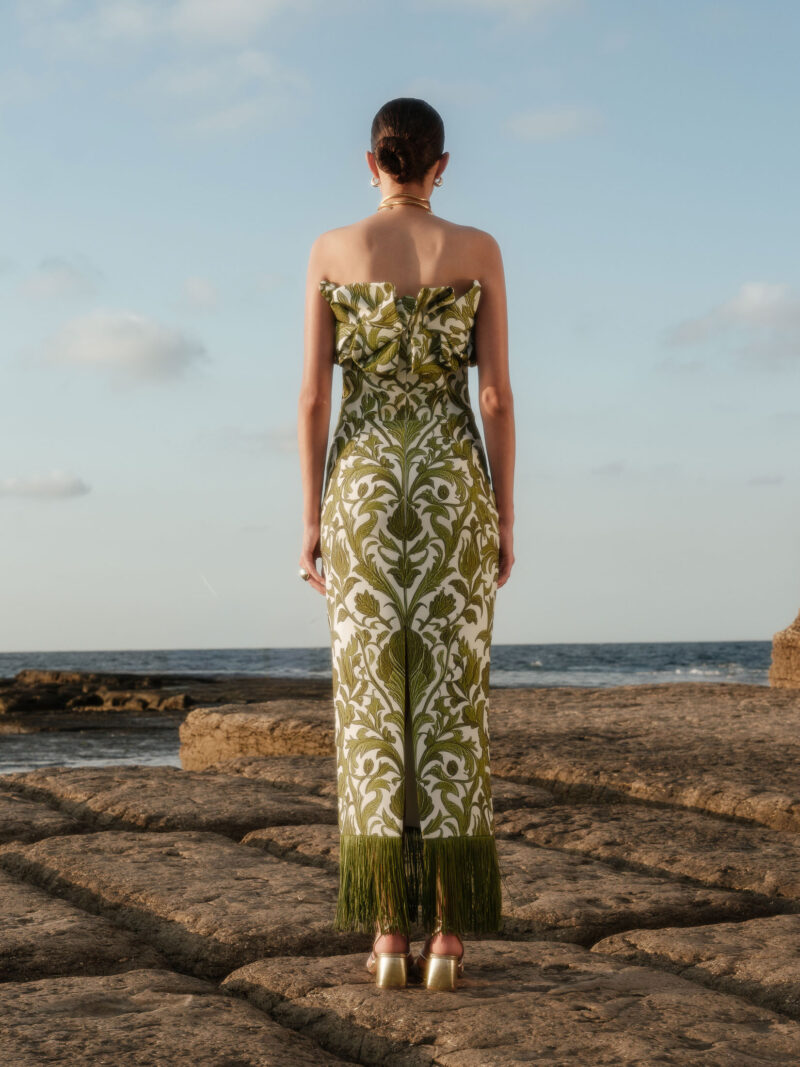 Back view of Aelia Strapless Maxi Dress featuring olive botanical print, ruffled neckline, and long fringe hem.