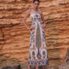 Model wearing the Nana Gotti Yara ivory printed linen strapless maxi dress with colorful Anatolian-inspired botanical motifs against a sandstone backdrop.