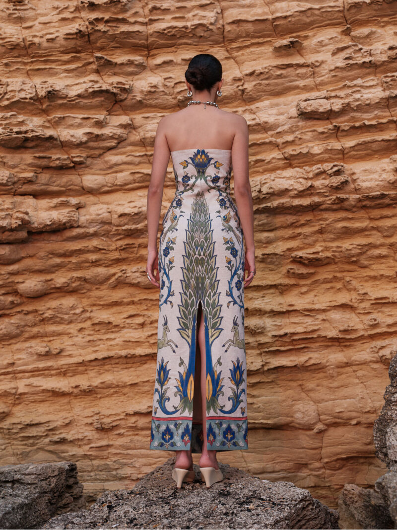 Back view of the Nana Gotti Yara printed linen strapless maxi dress with a fitted waist, colorful botanical pattern and elegant center-back slit